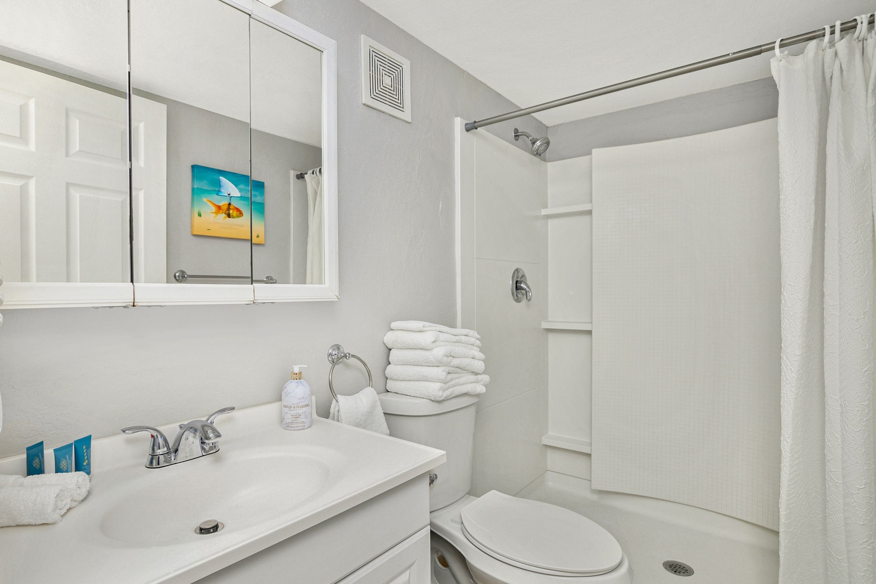 A bathroom with a white sink, a toilet, and a shower.