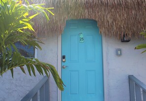 A turquoise door with a number 25 sign, a thatched roof, and a small wall-mounted light fixture. - Latitude 26 Waterfront Resort & Marina (Fort Myers Beach)