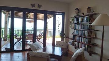 A room with a sliding glass door leading to an outdoor area, a bookshelf, and a table with chairs.