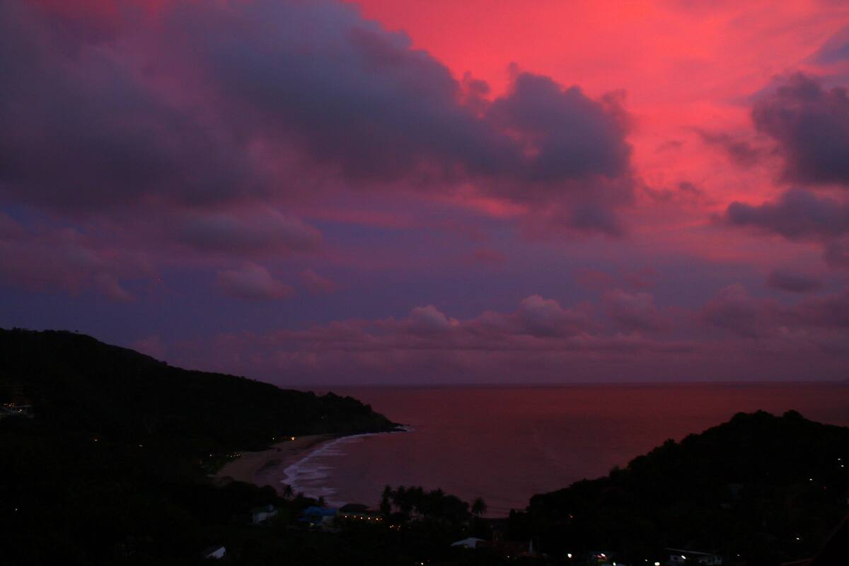 Un paisaje costero con playa y colinas durante el crepúsculo.