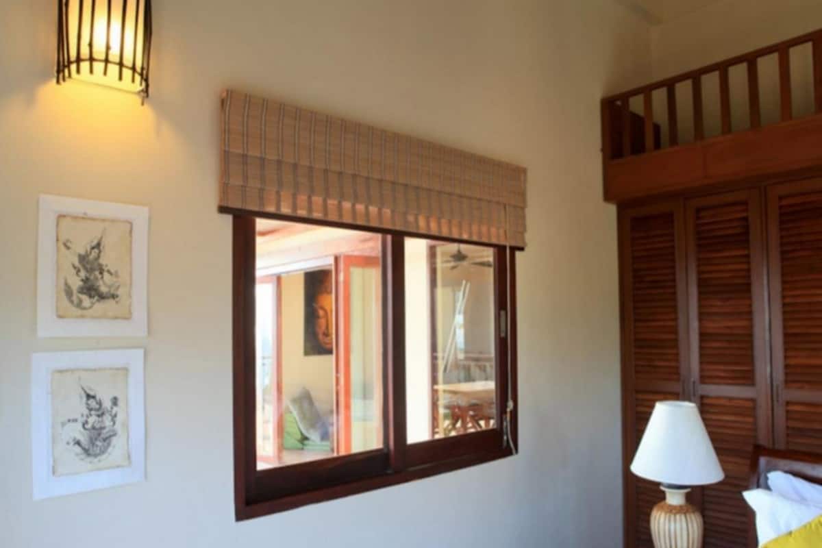Una habitación con ventana, lámpara y obras de arte en la pared.