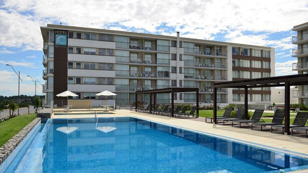 Un hotel con piscina, mobiliario exterior y varios balcones.