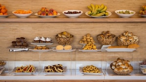 A buffet with various food items including fruits, pastries, and bread. - Real Colonia Hotel & Suites (Colonia del Sacramento)