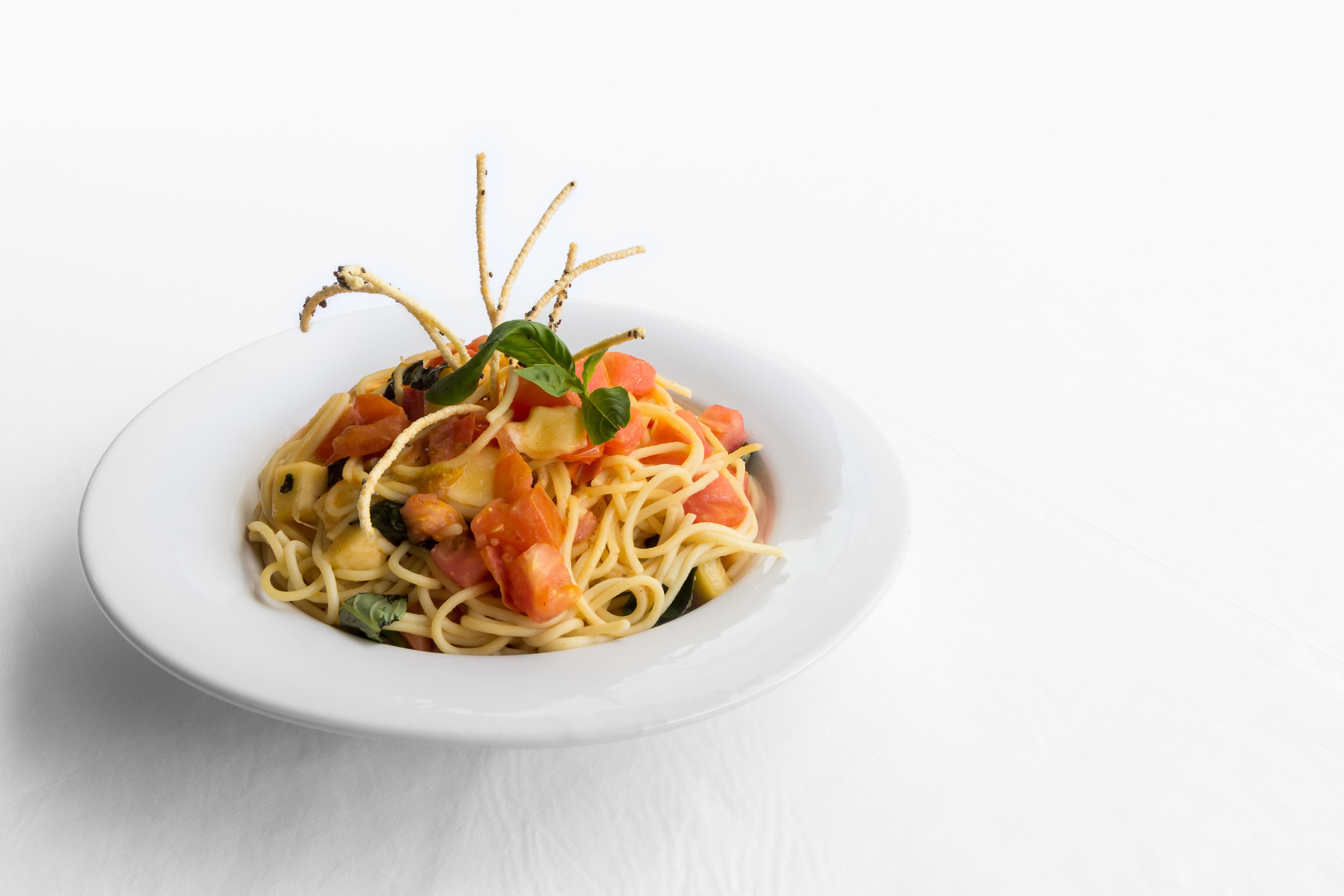 A plate of spaghetti with shrimp, tomatoes, and basil.
