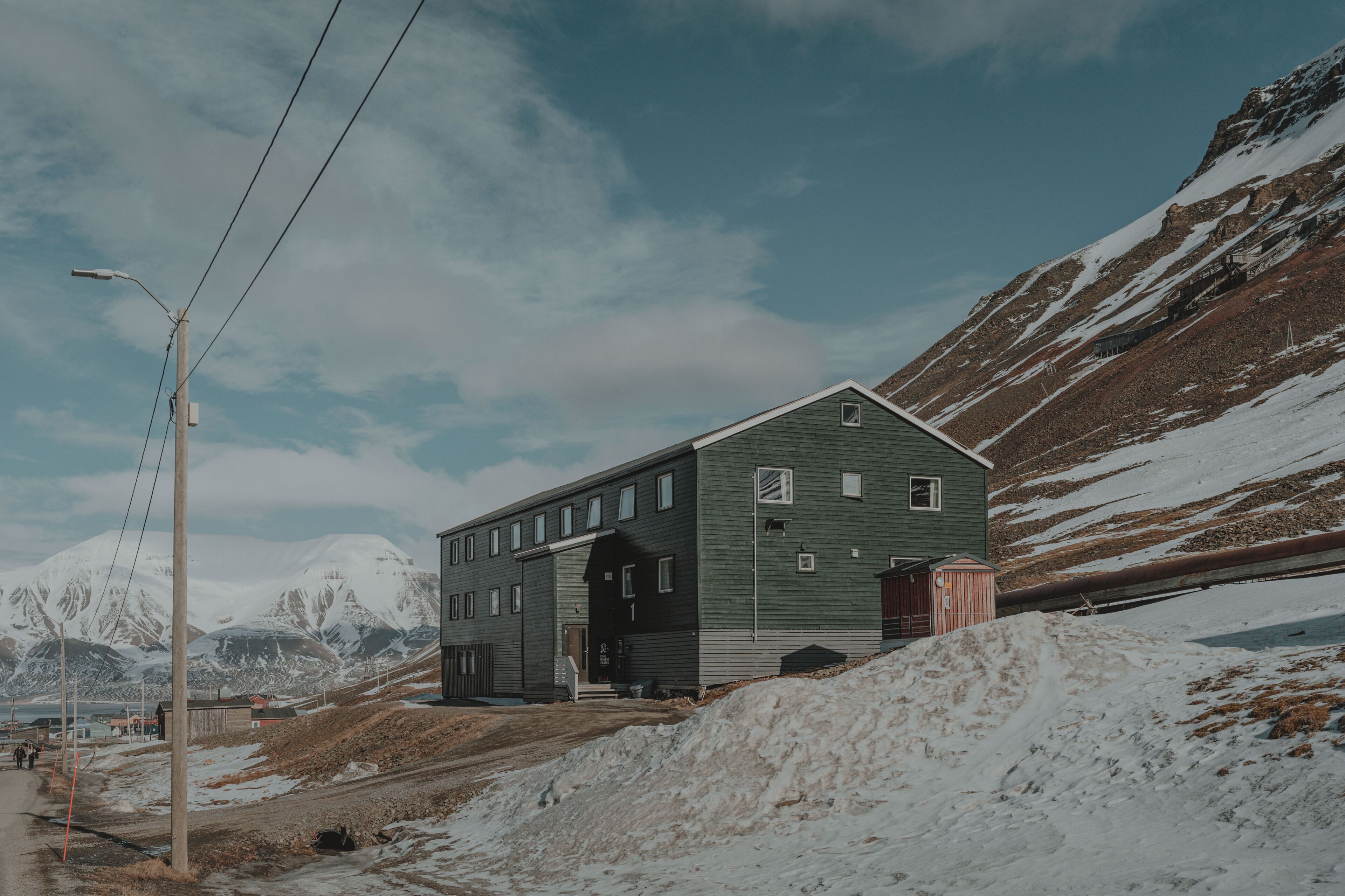 Un edificio di due piani con un'ampia porta ad arco, immerso in una zona montana innevata sotto un cielo sereno.