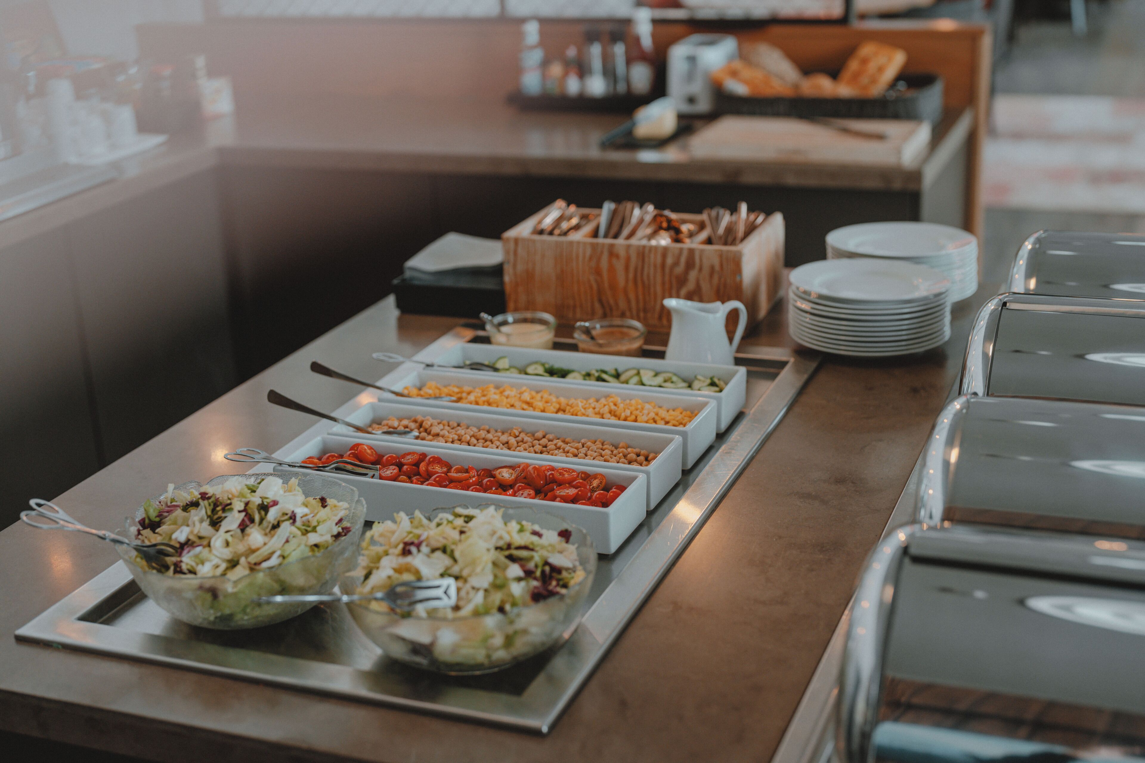 Un bufé con diversas opciones de comida, como ensaladas, frijoles y tomates.