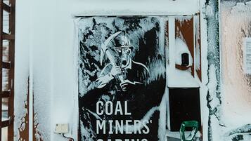 Un edificio con un cartel que dice 'Coal Miners' Cabins' y una pala verde apoyada en la pared.