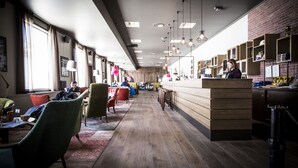 A modern interior with a long counter, wooden flooring, and green upholstered chairs.