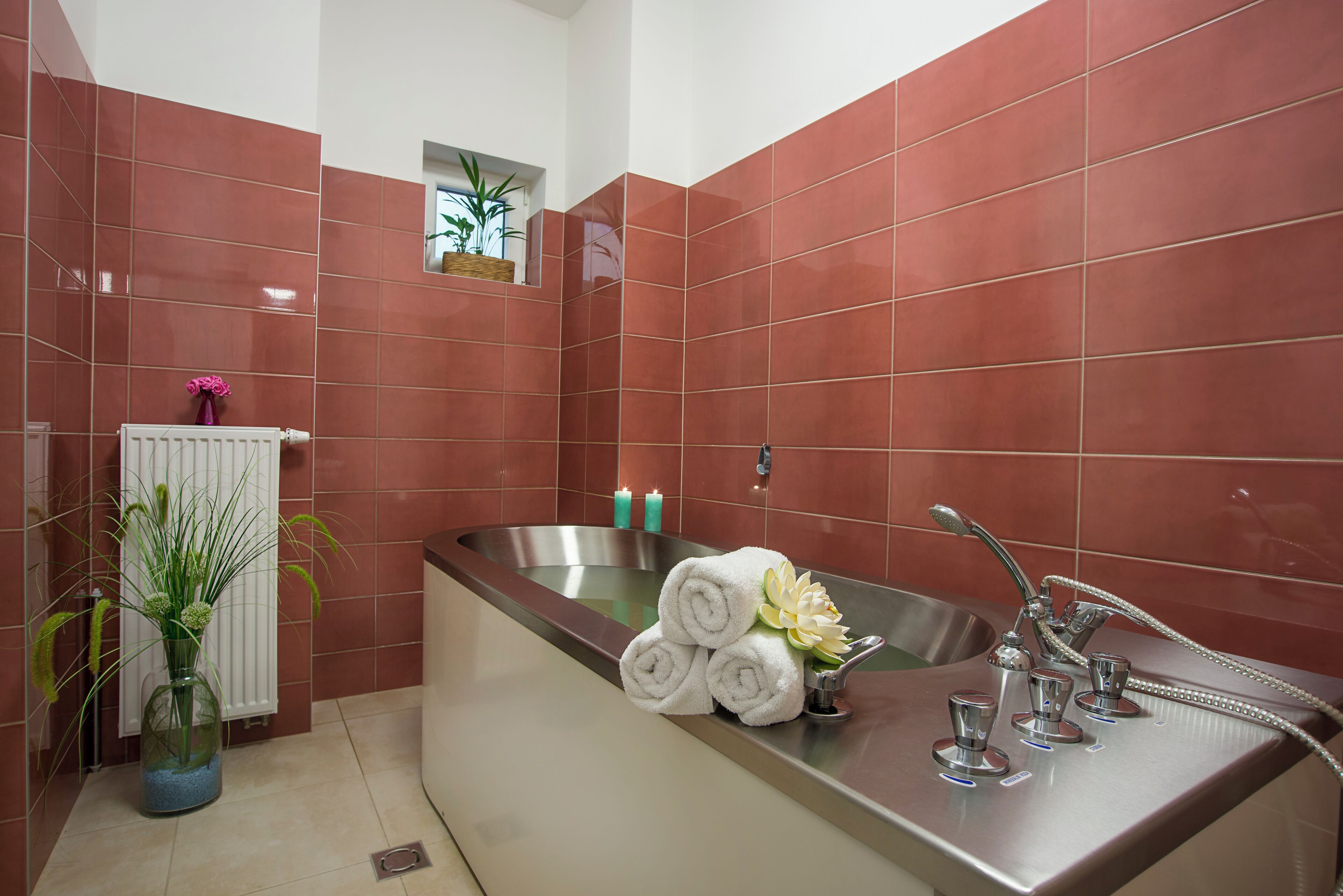 Ein modernes Badezimmer mit einer Badewanne, einem Waschbecken mit Handbrause und einer Topfpflanze.