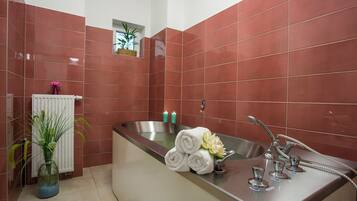 Ein modernes Badezimmer mit einer Badewanne, einem Waschbecken mit Handbrause und einer Topfpflanze.