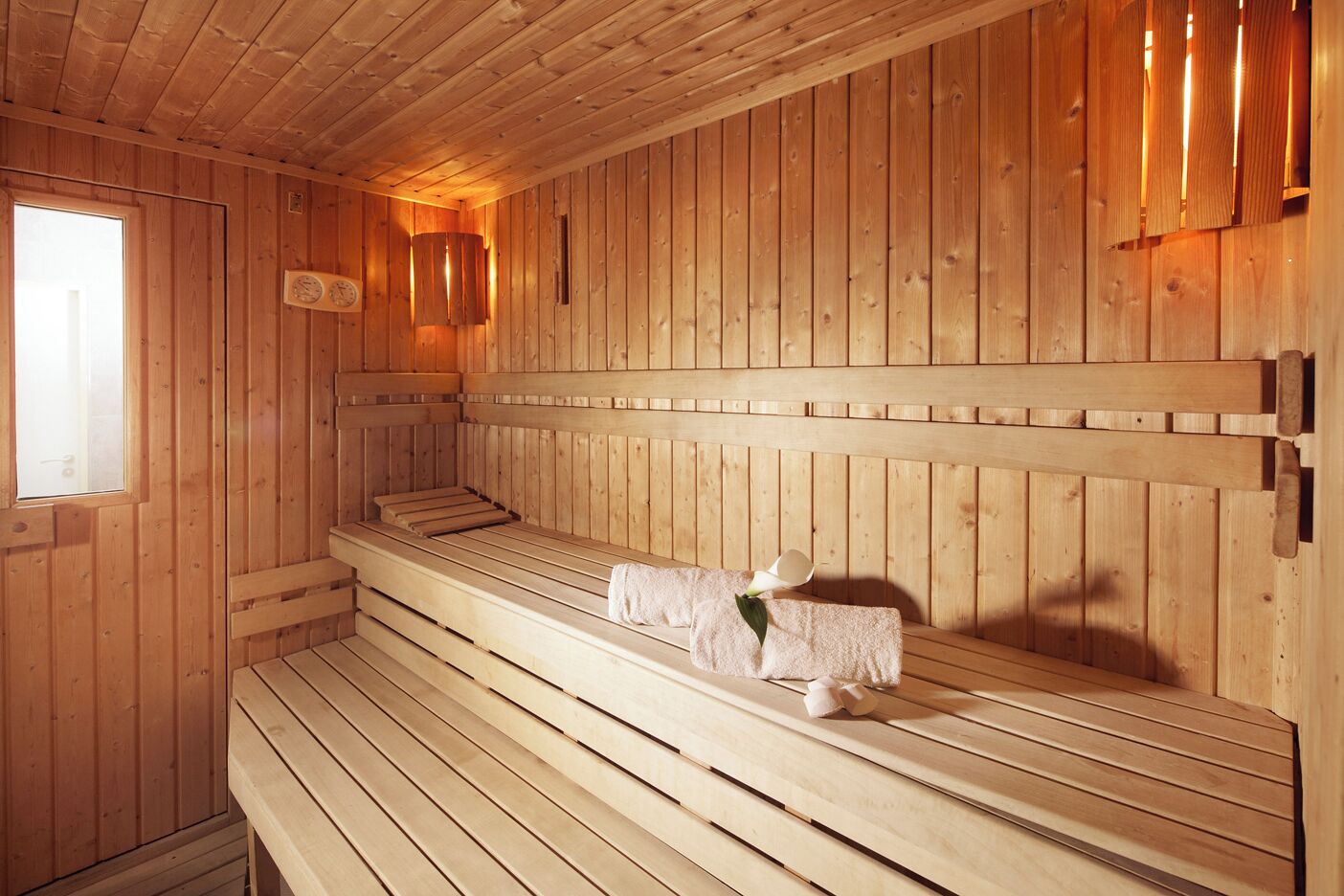 A wooden sauna with benches and a clock on the wall.