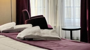 Una habitación de hotel con cama, una silla, una mesa y una lámpara.