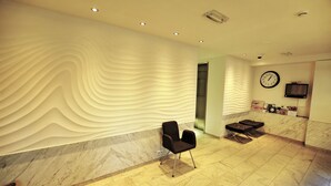 Un vestíbulo con diseño moderno, que presenta una pared con textura, un reloj y un área de estar.