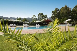 Una piscina al aire libre, sombrillas, sillones reclinables de piscina
