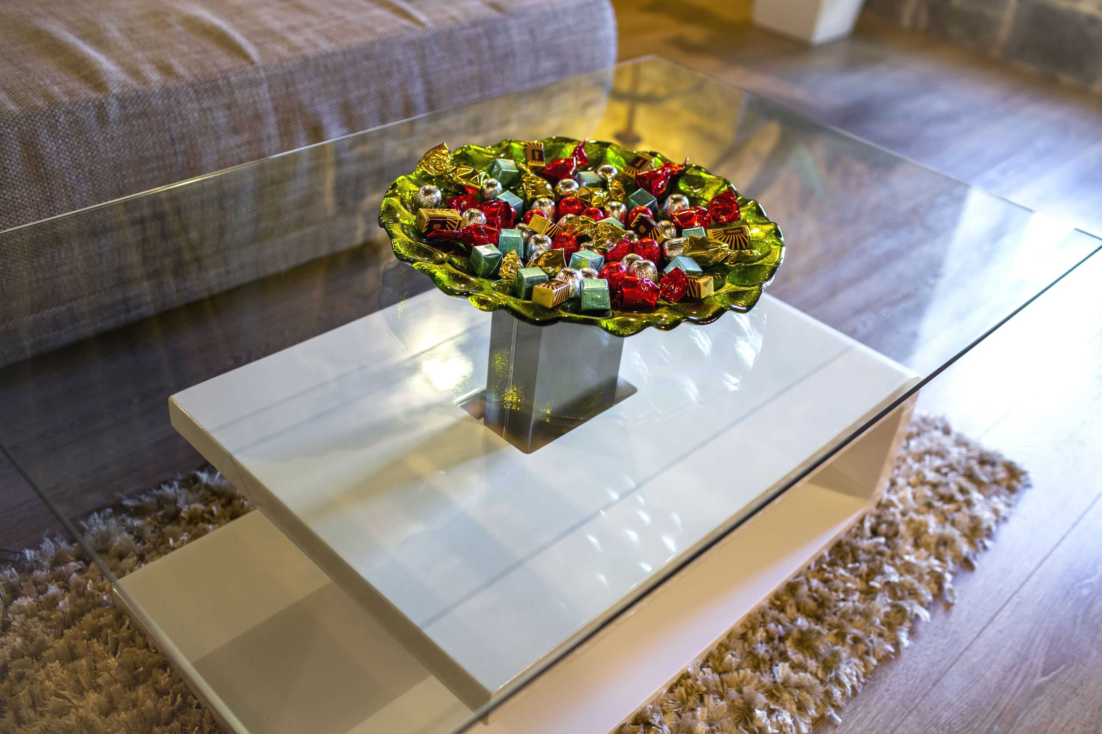 A glass coffee table with a decorative bowl on top.