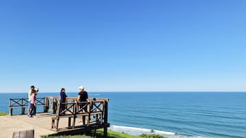 A wooden deck overlooking the ocean with a clear sky.
