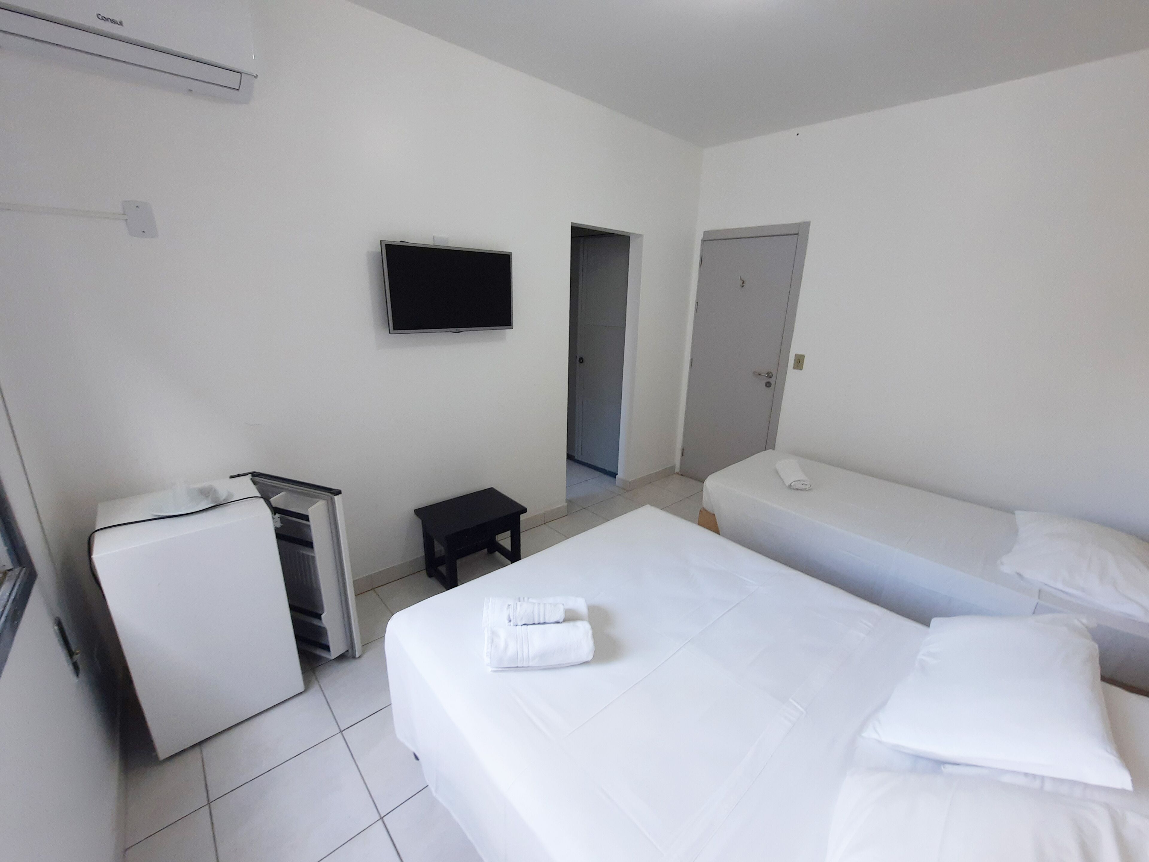 A hotel room with a bed, a desk, a television, and a door.