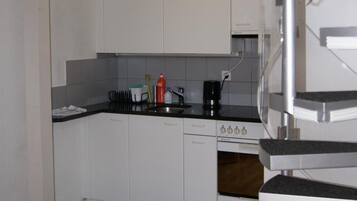 A modern kitchen with white cabinets, a black countertop, and a stainless steel range hood.
