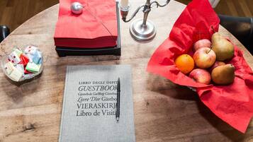 Ein Holztisch mit Gästebuch, Kerze und Obstkorb.