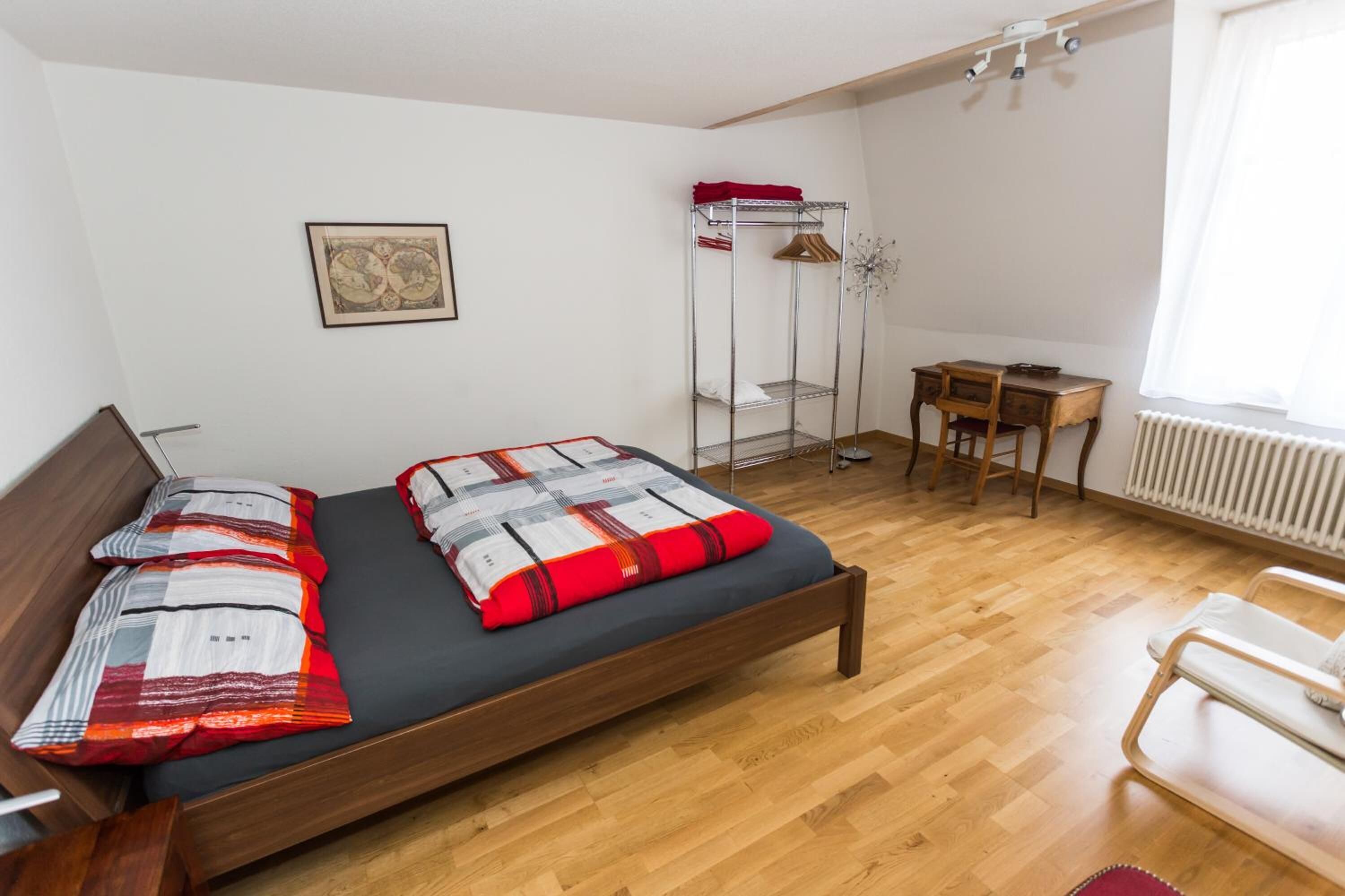A bedroom with a wooden bed, a desk, and a chair.