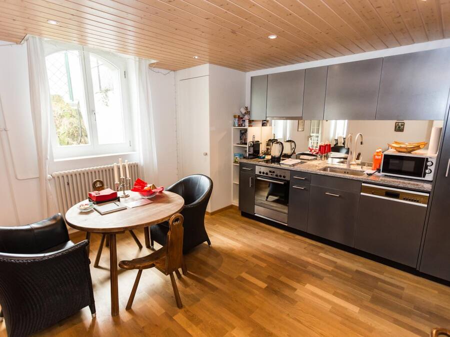 Una cocina moderna con armarios oscuros, una mesa de comedor de madera y dos sillas.