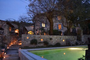 Un edificio de piedra con una piscina, escalones que conducen a una puerta y una banca.