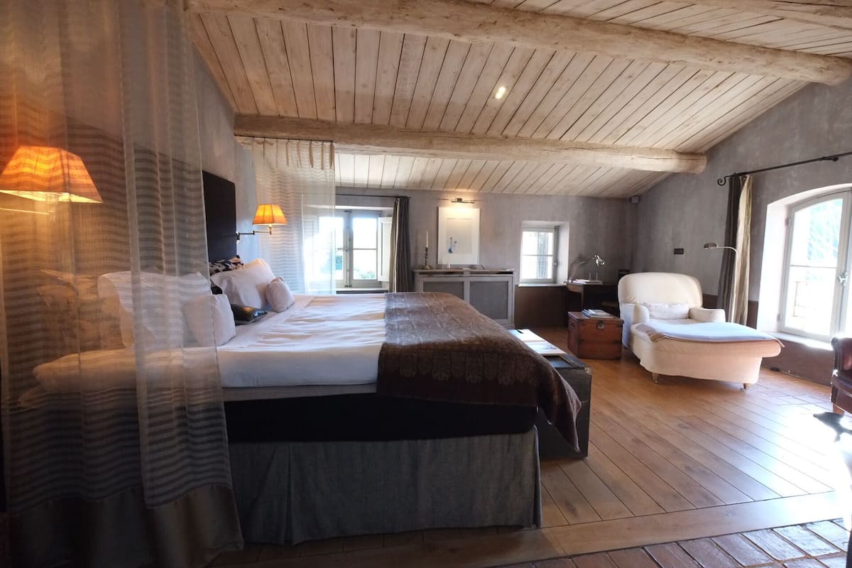 A spacious bedroom with a large bed, a chair, and a desk.