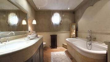 Une salle de bain avec une grande baignoire, deux lavabos, un miroir et un radiateur.