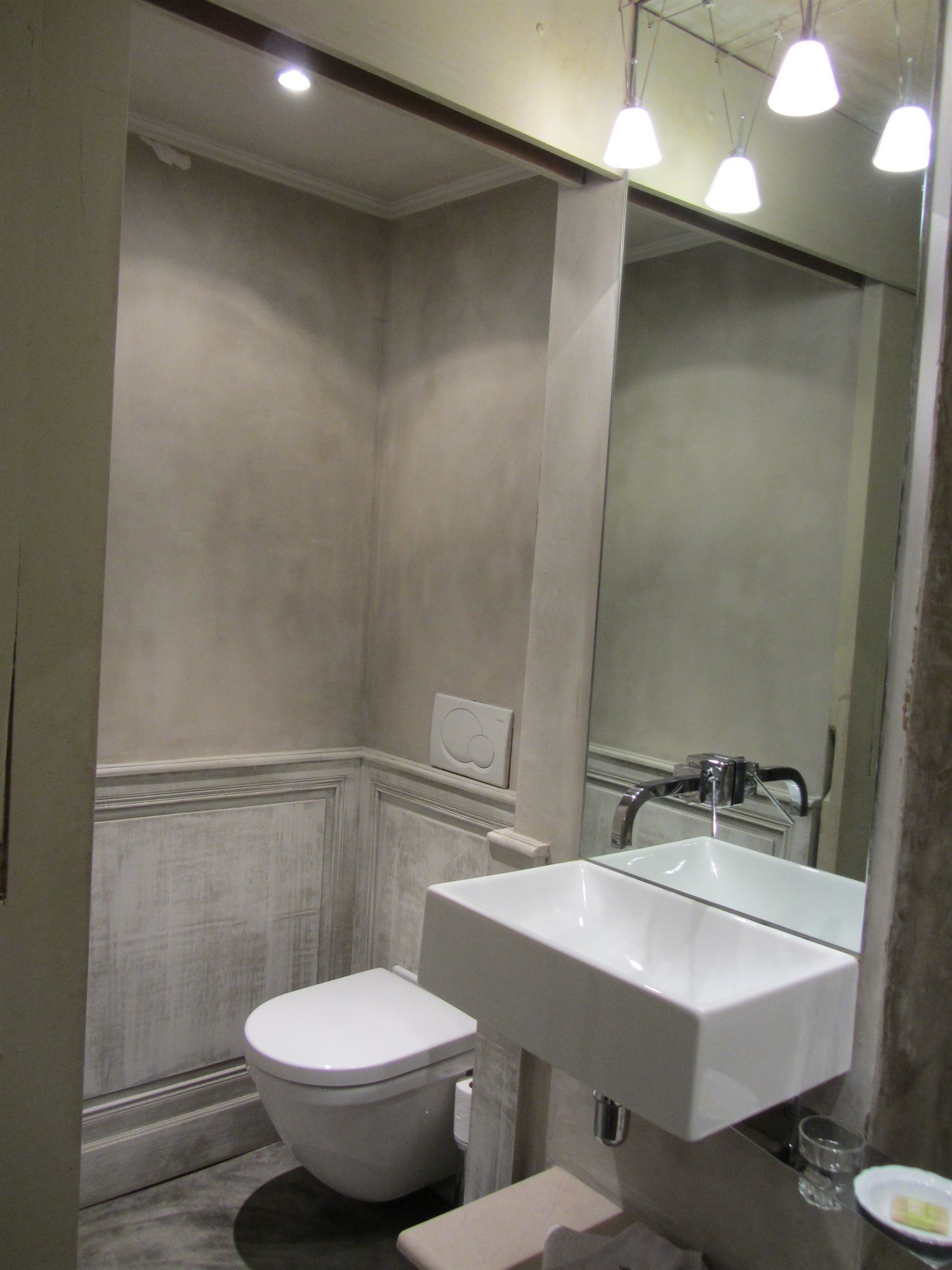 A bathroom with a toilet, a sink, and a mirror.