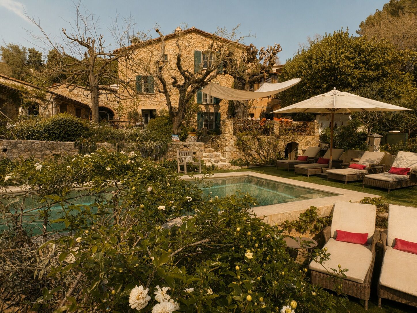 A pool area with lounge chairs and a stone building in the background.