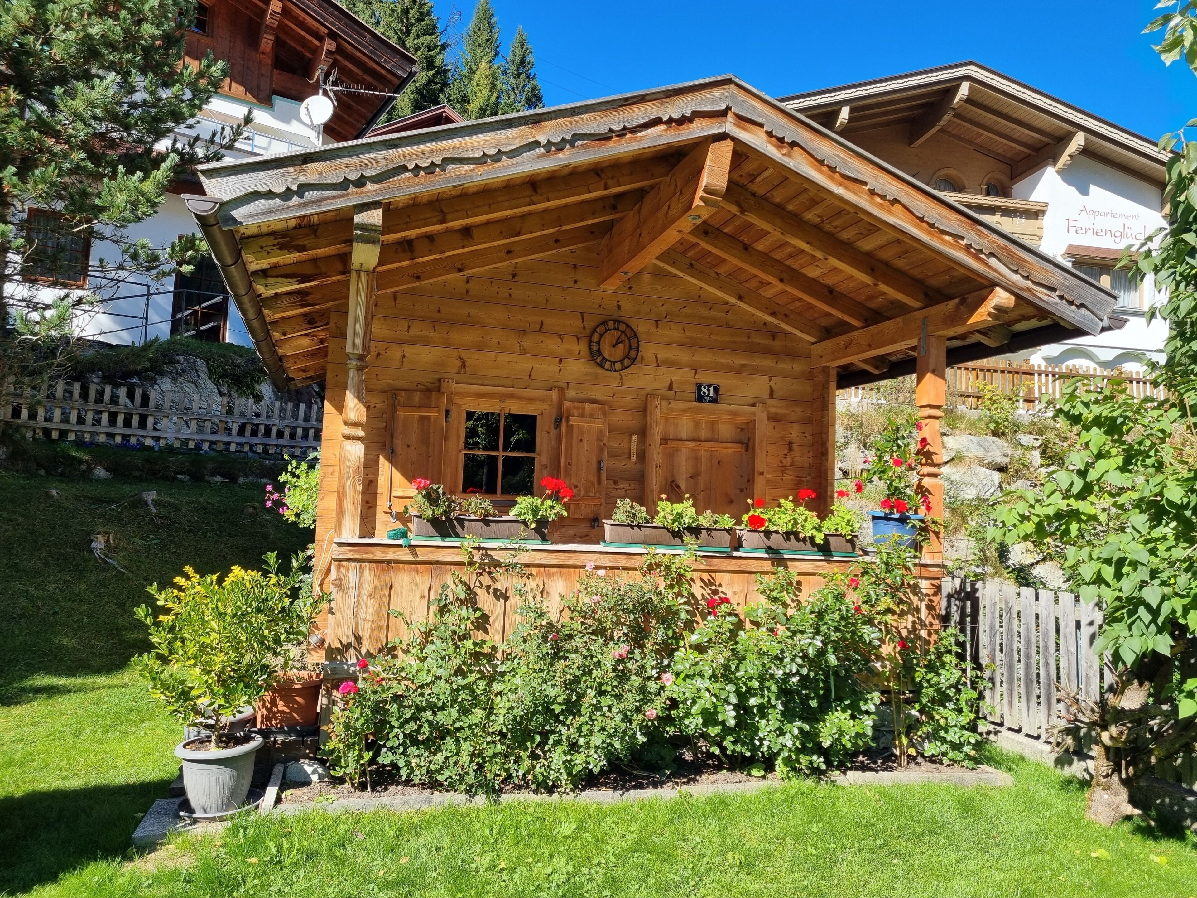 Una baita di legno con un portico coperto, un orologio e un cartello che indica 'Apartment Ferienglück'.