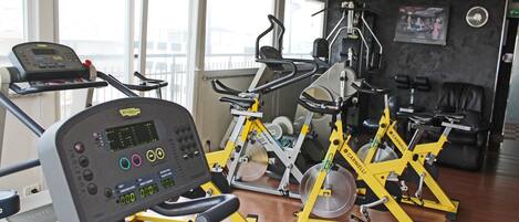 Un gimnasio con máquinas de cardio, equipo de pesas y una cinta de correr.