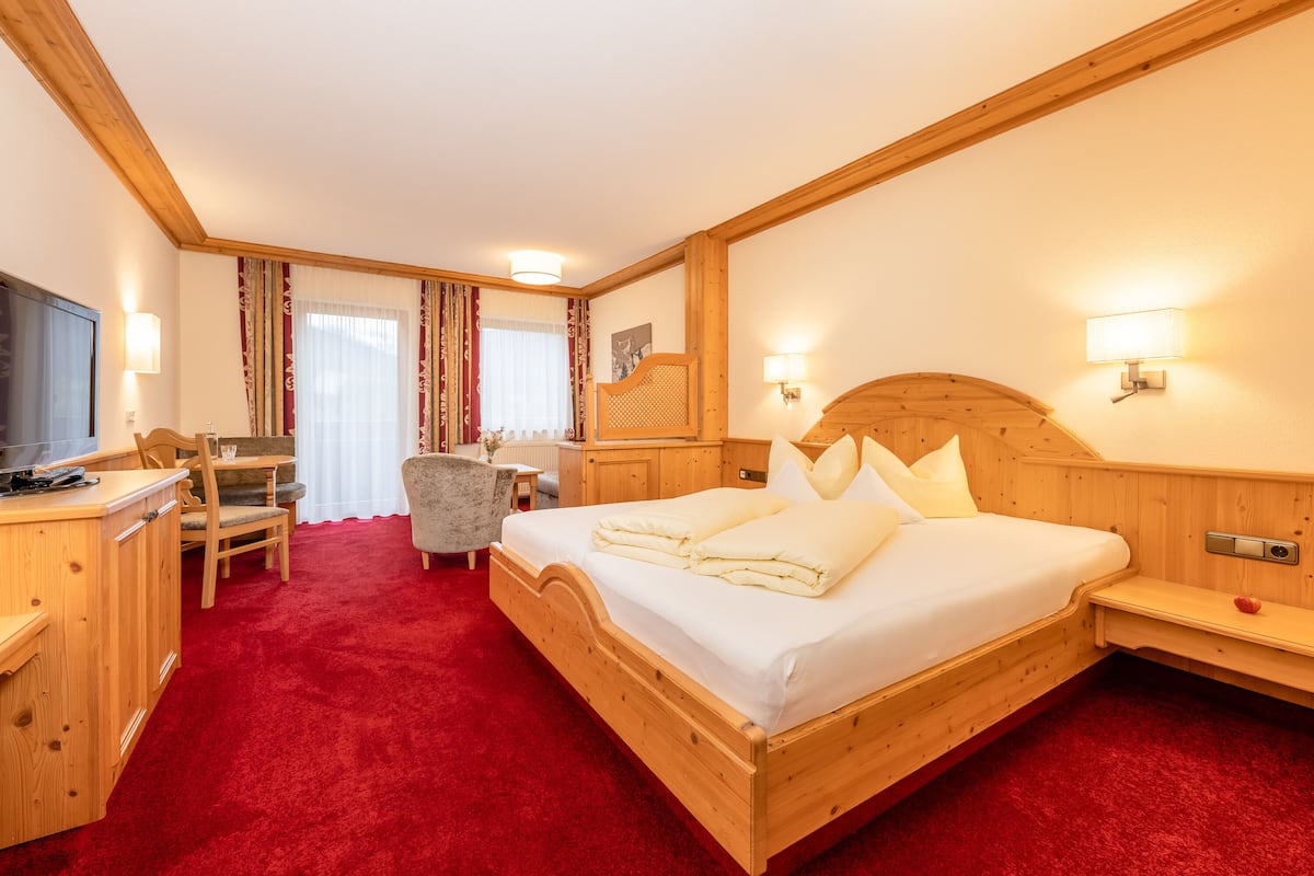A hotel room with a wooden bed, a desk, a chair, and a television.