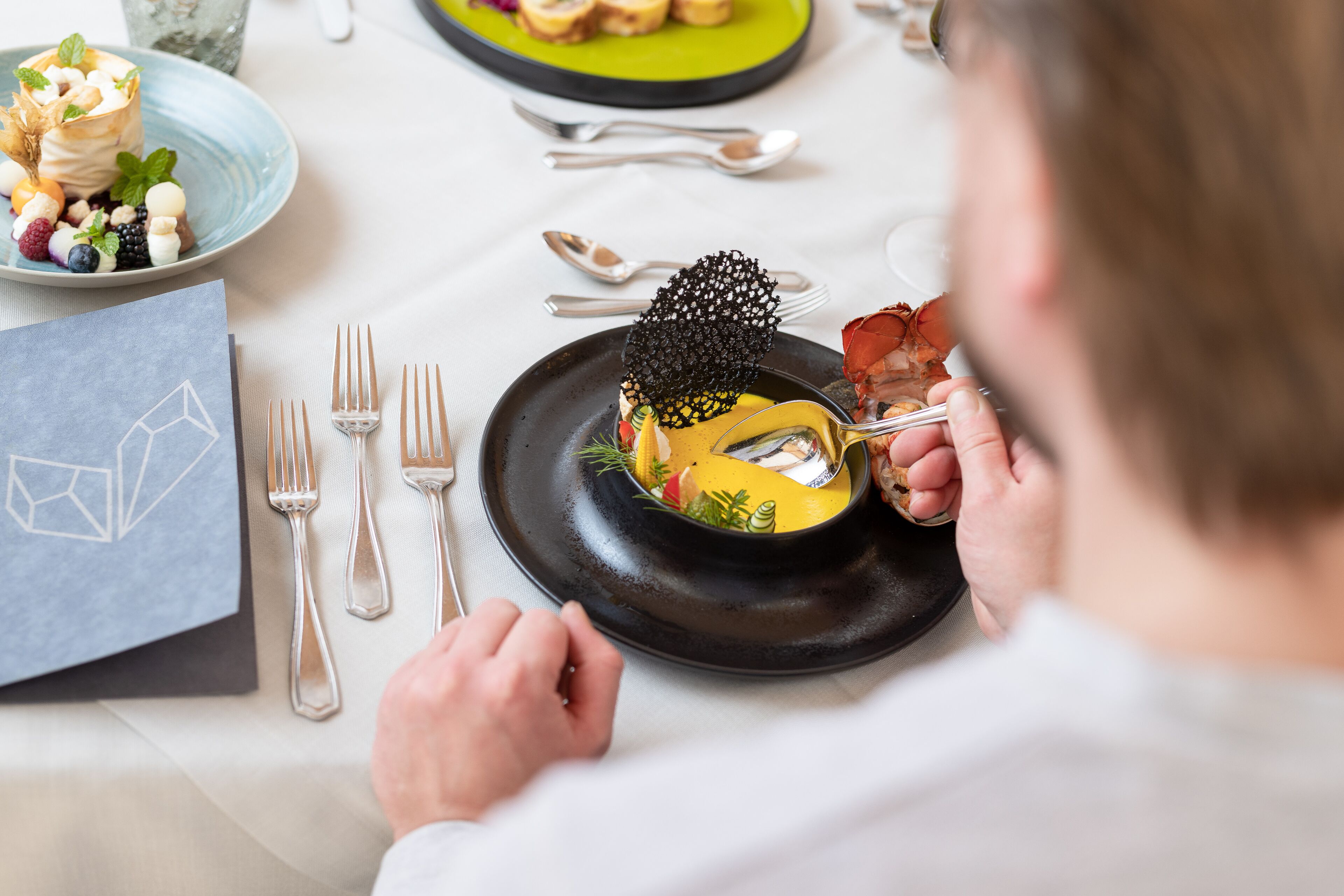Une table à manger avec une assiette de nourriture, des couverts et une serviette.