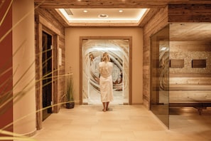 Una persona vestida de blanco parada en un pasillo con paredes de madera y un vidrio que da a una escalera.