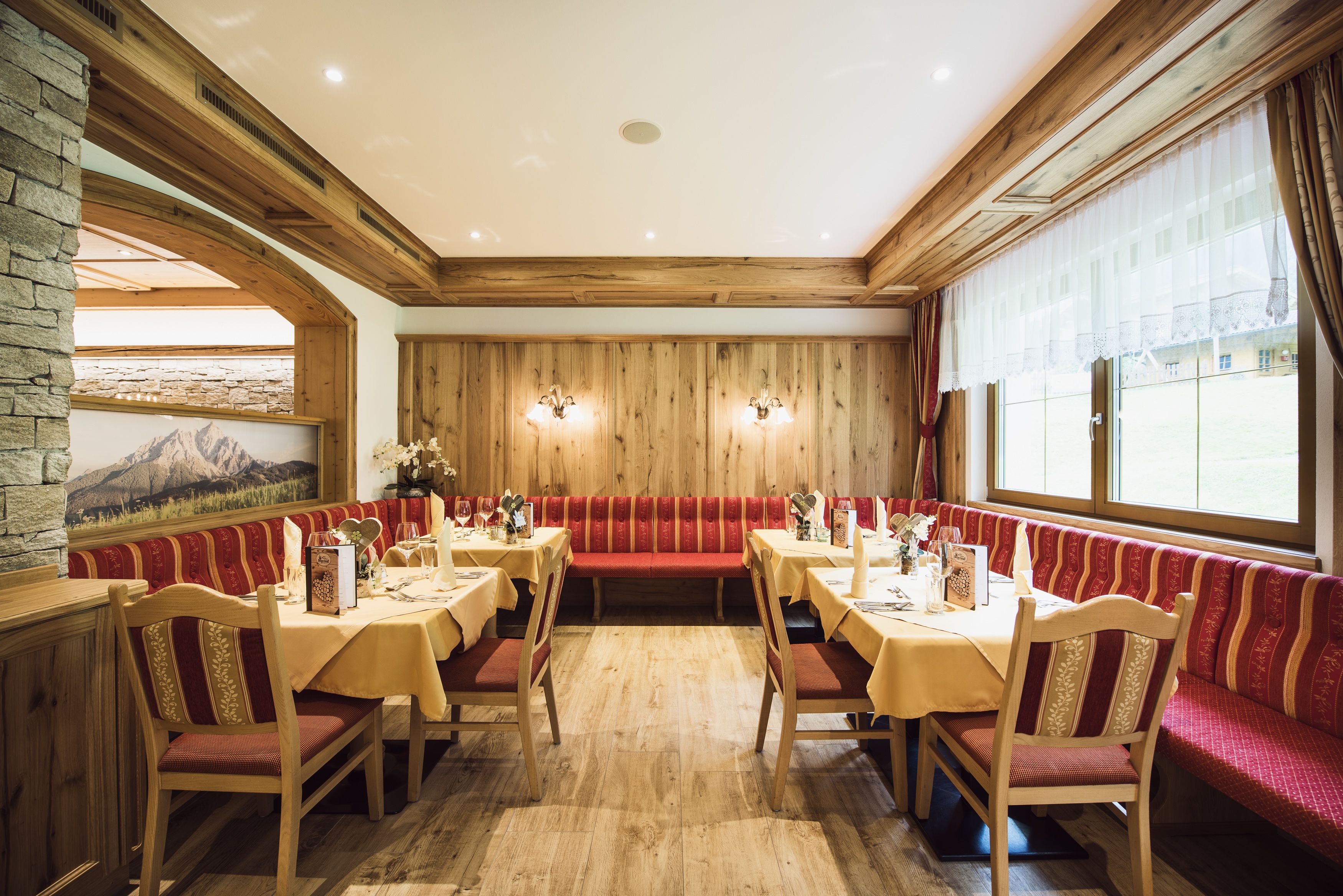 Un restaurante con paredes de madera, bancos rojos y mesas preparadas para comer.