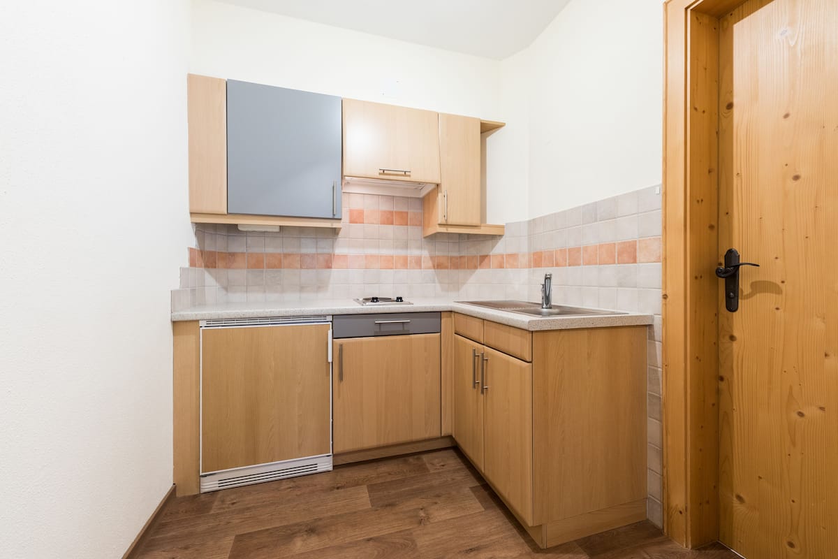A compact kitchen with wooden cabinets, a dishwasher, and a sink.