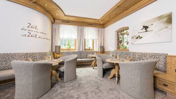 Una habitación acogedora con techo de madera, un sofá, dos sillones, una mesita y una ventana con cortinas.