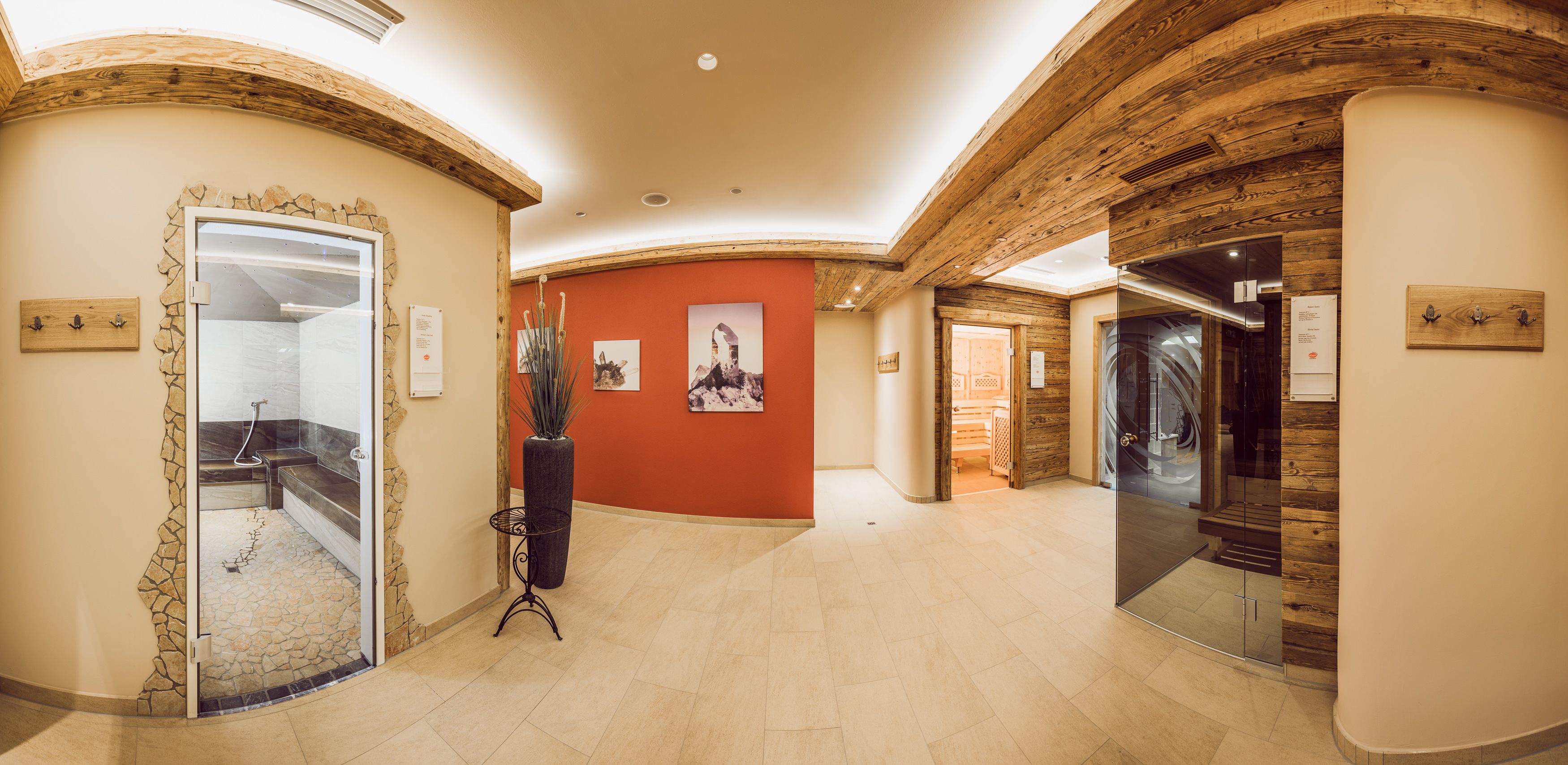A spacious hallway with a stone wall, a glass shower enclosure, and a wooden ceiling.