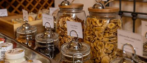 A variety of food items in glass jars with labels, including chips and dried fruits.