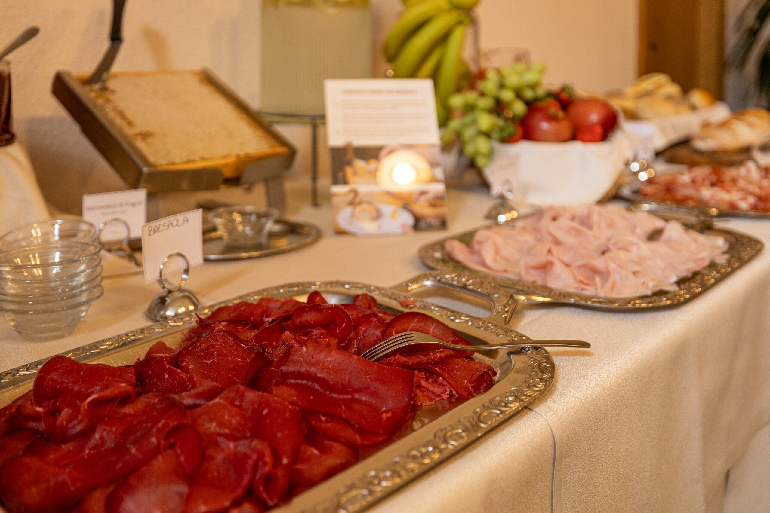 A buffet table with various food items, including sliced meats and a cheese board.