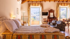 Quarto com cama, televisão, teto de madeira, janela com cortinas e vista para o exterior.