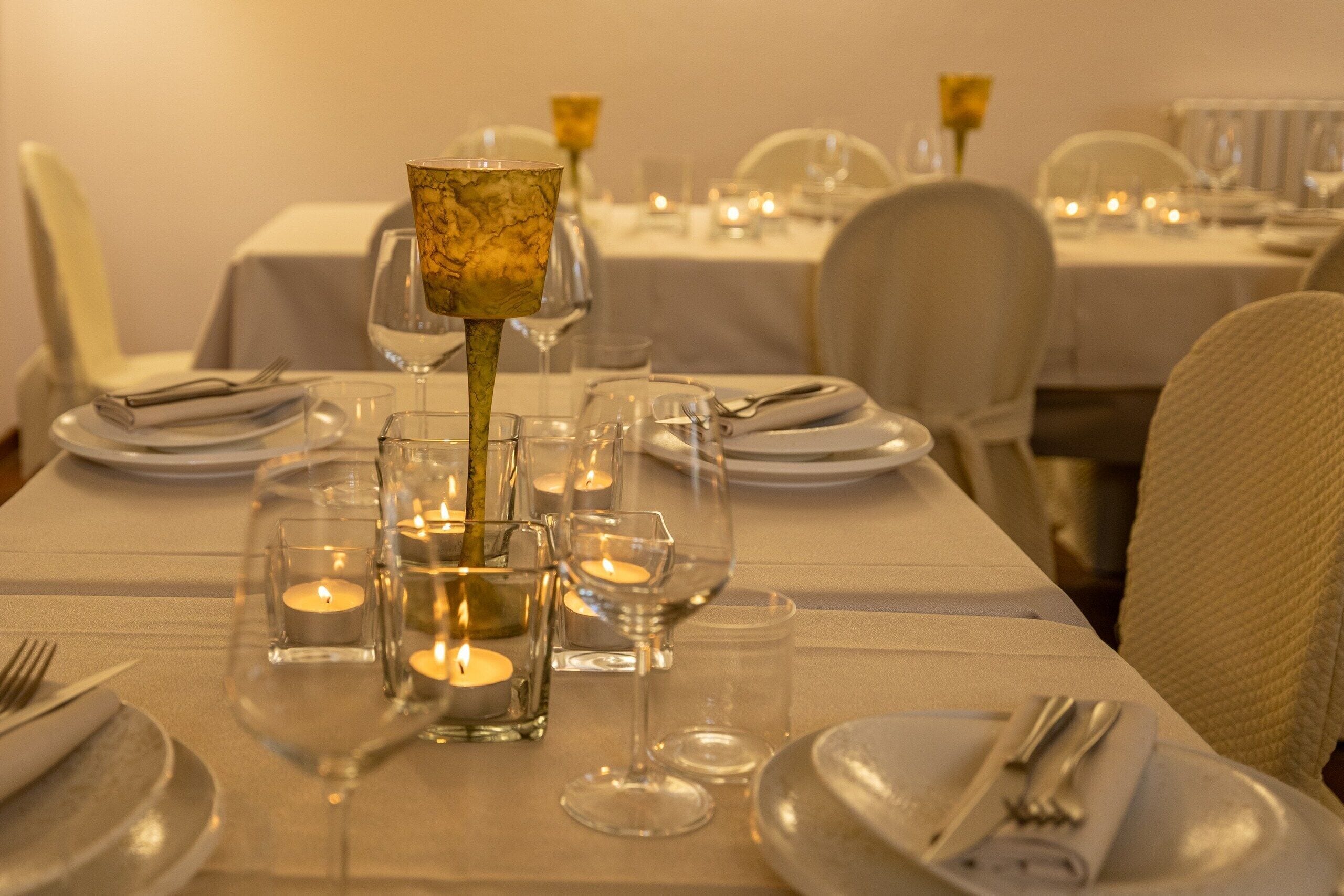 A dining table set with plates, glasses, and candles, indicating a formal dining arrangement.