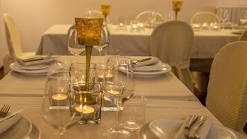 A dining table set with plates, glasses, and candles, indicating a formal dining arrangement.
