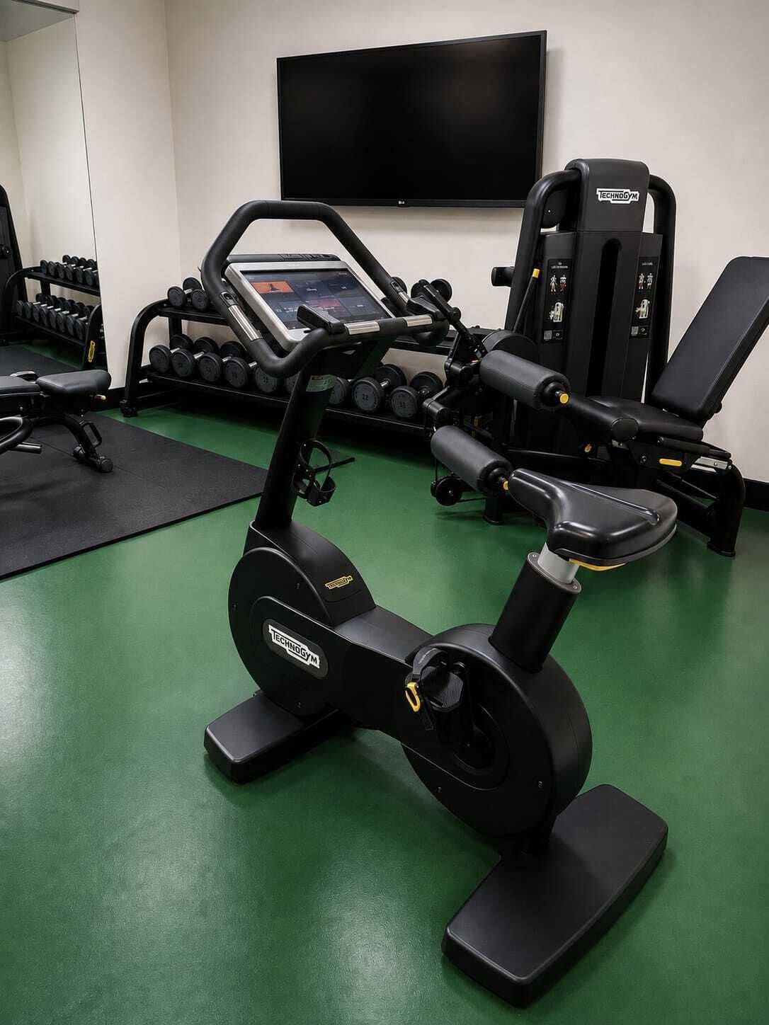 A gym with exercise equipment, a television, and a wall-mounted TV.