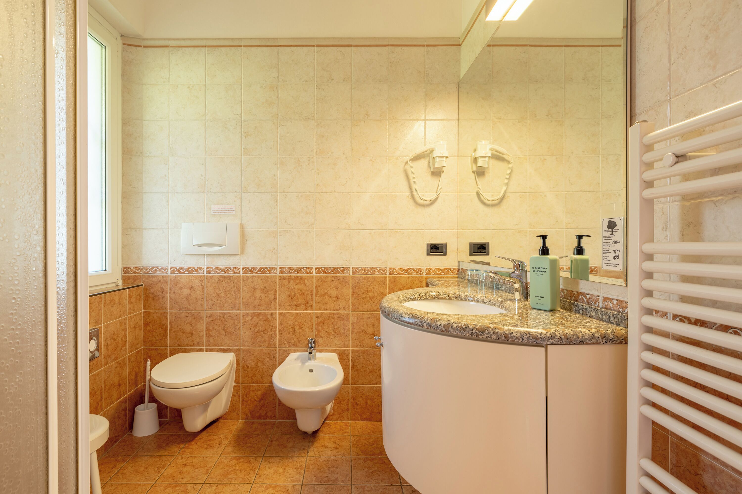 A bathroom with a toilet, bidet, sink, and towel rack.