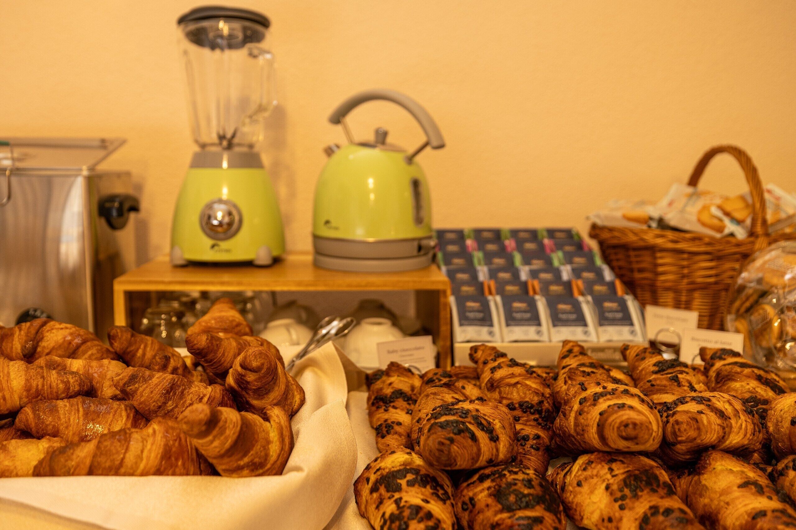Un coin cuisine équipé d’un mixeur, d’une bouilloire et d’un panier de viennoiseries.
