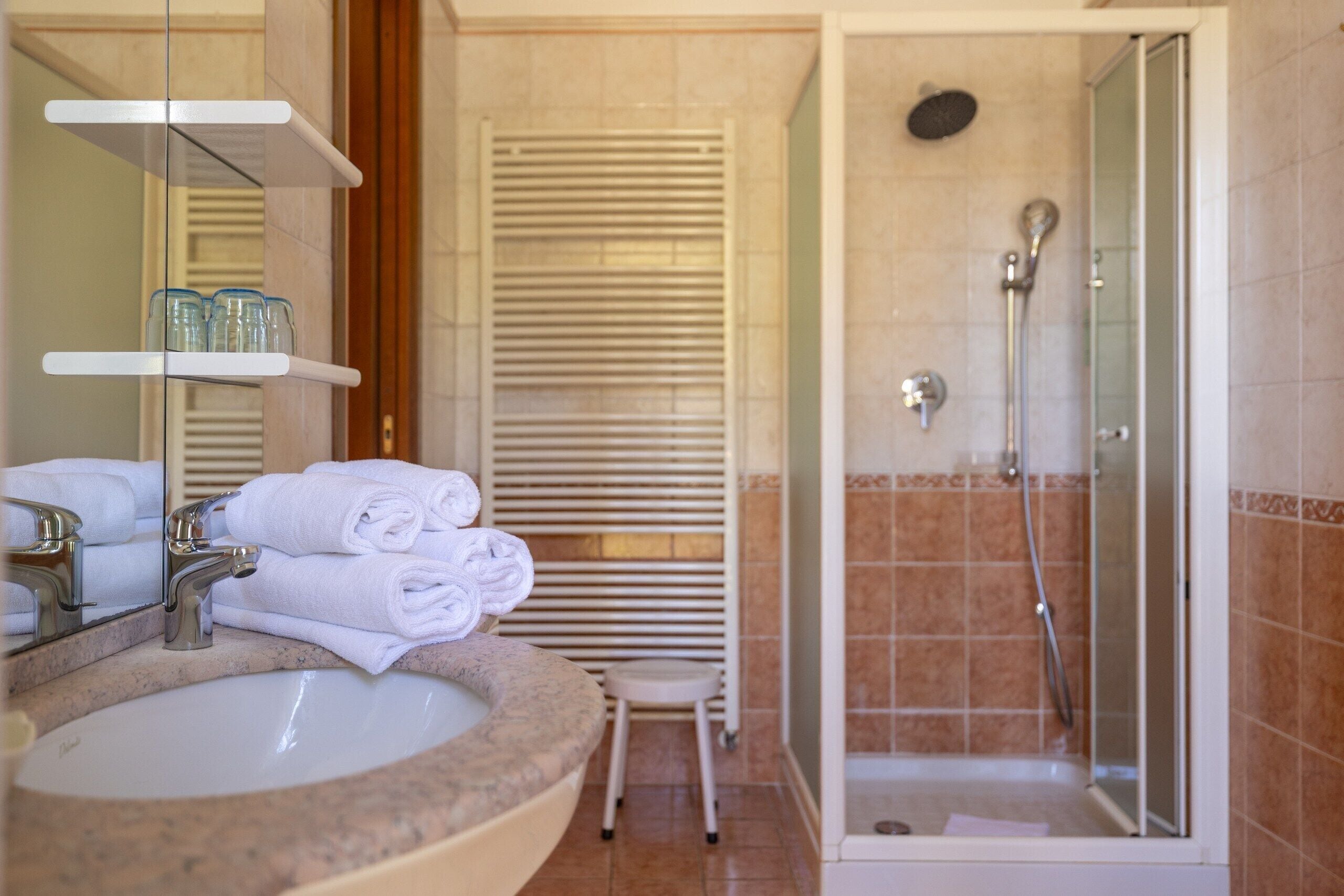 A bathroom with a sink, mirror, towel rack, and shower.