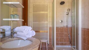 A bathroom with a sink, mirror, towel rack, and shower.