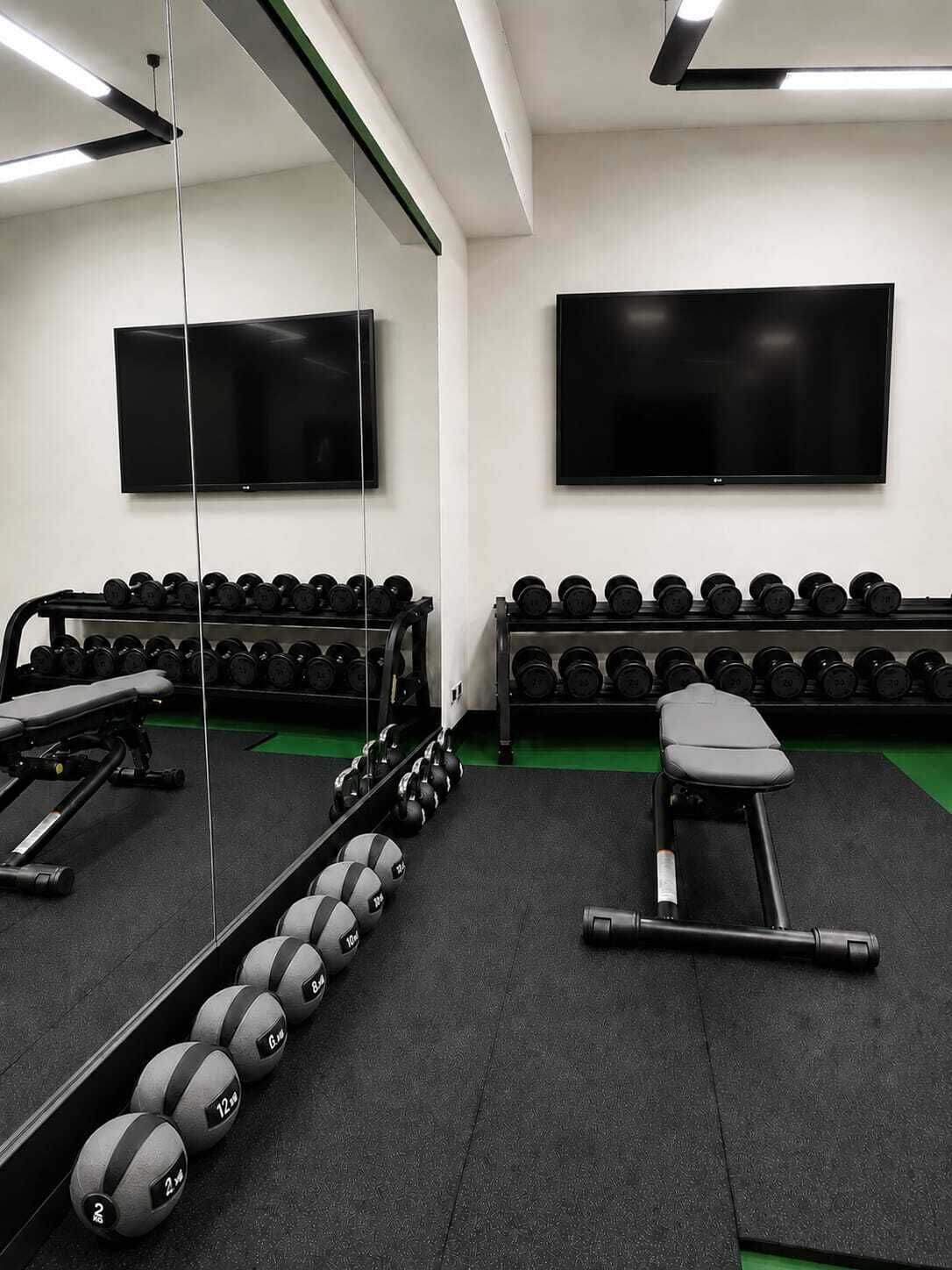 A gym with exercise equipment, a bench, and a mirror.
